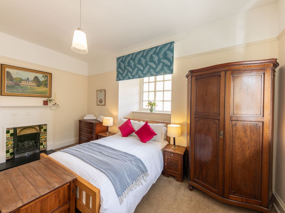 A bedroom with a bed, wardrobe and fireplace at Bishop Lightfoot Cottage in Bishop Auckland