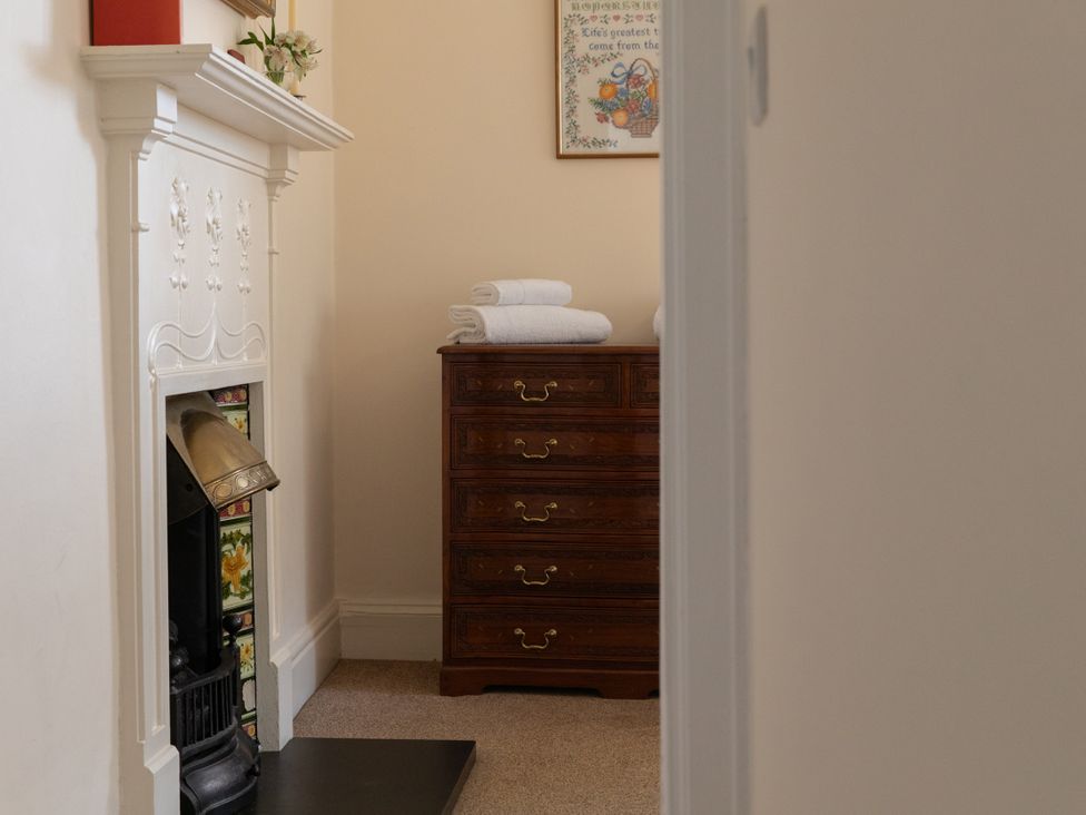 A sitting room with a fireplace and a chest of drawers at Bishop Lightfoot Cottage in Bishop Auckland
