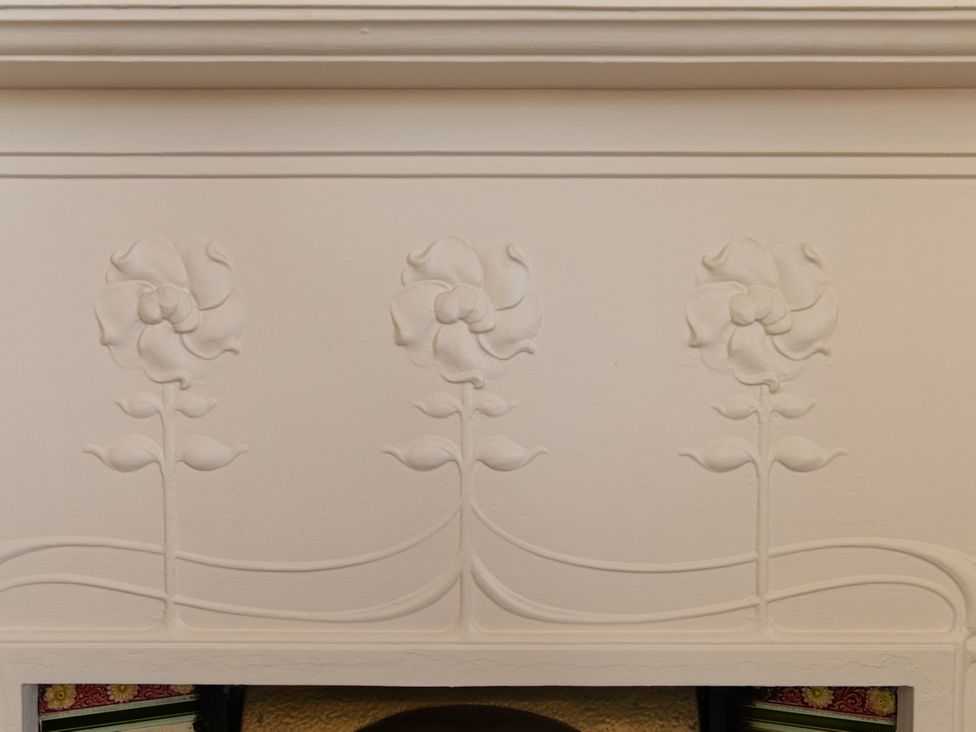 A wall with flower decorations above a fireplace at Bishop Lightfoot Cottage in Bishop Auckland
