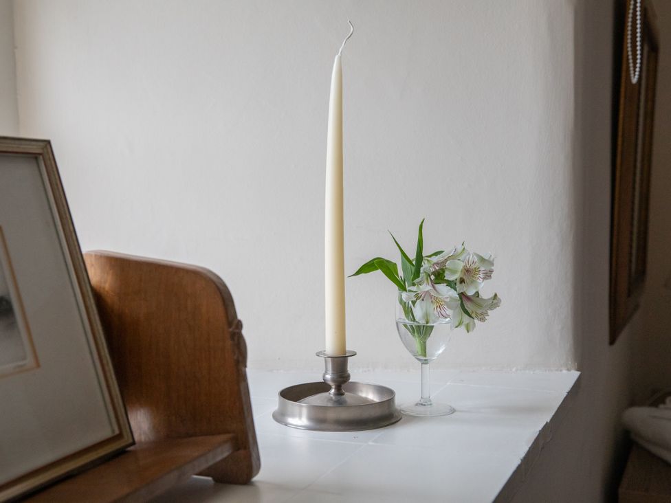 A candle and flowers on a windowsill at Bishop Lightfoot Cottage in Bishop Auckland