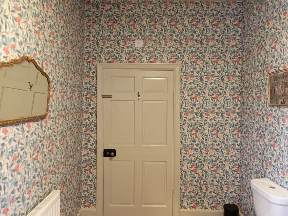 A bathroom with floral wallpaper and a door at Bishop Lightfoot Cottage in Bishop Auckland