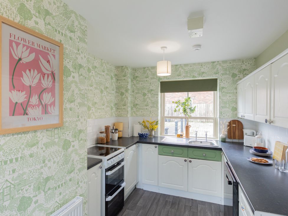 A kitchen with cabinets and utensils at Sheriff's Tower Cottage - East Bishop Auckland