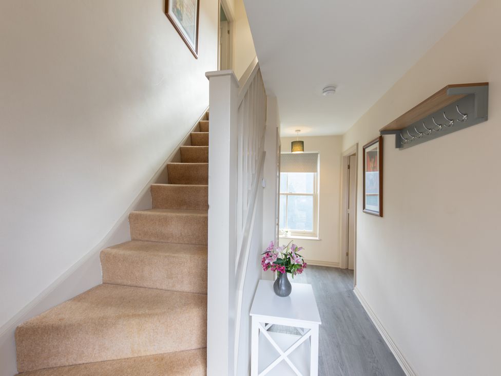 A hallway with a staircase and table at Sheriff's Tower Cottage - East in Bishop Auckland