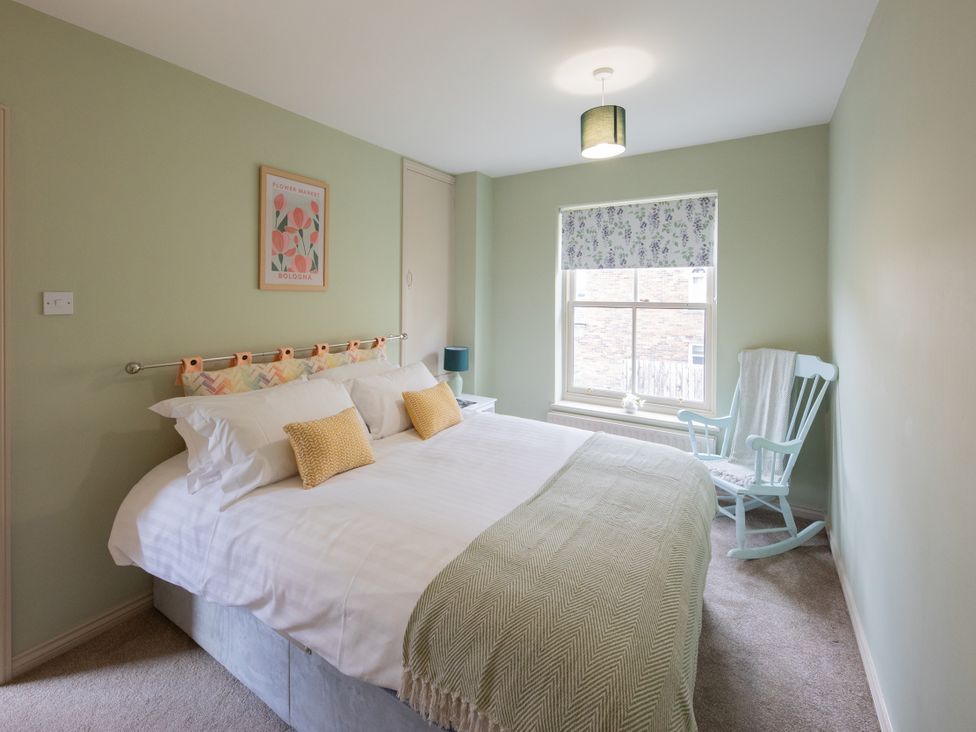 A bedroom with a bed and rocking chair at Sheriff's Tower Cottage - East Bishop Auckland
