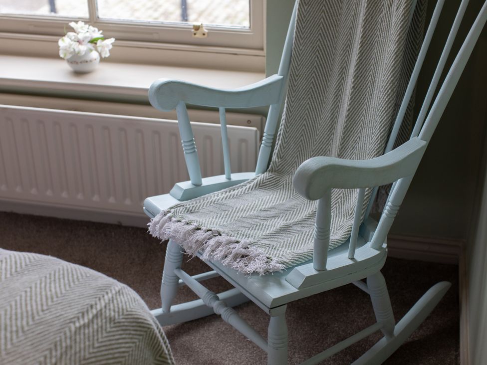 A rocking chair with a blanket in a bedroom at Sheriff's Tower Cottage - East, Bishop Auckland