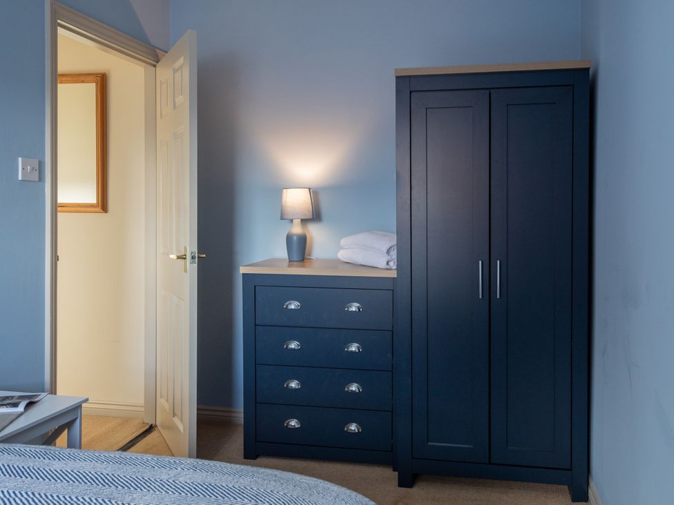 A bedroom with a wardrobe, chest of drawers and lamp at Sheriff's Tower Cottage - East, Bishop Auckland