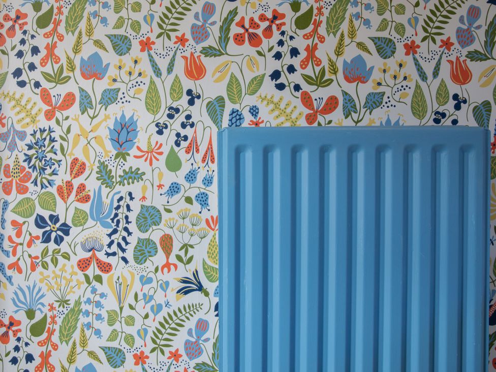 A blue radiator against flower wallpaper at Sheriff's Tower Cottage - East in Bishop Auckland