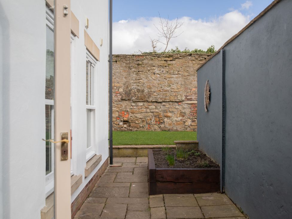 A garden view with a door and stone wall at Sheriff's Tower Cottage - East, Bishop Auckland