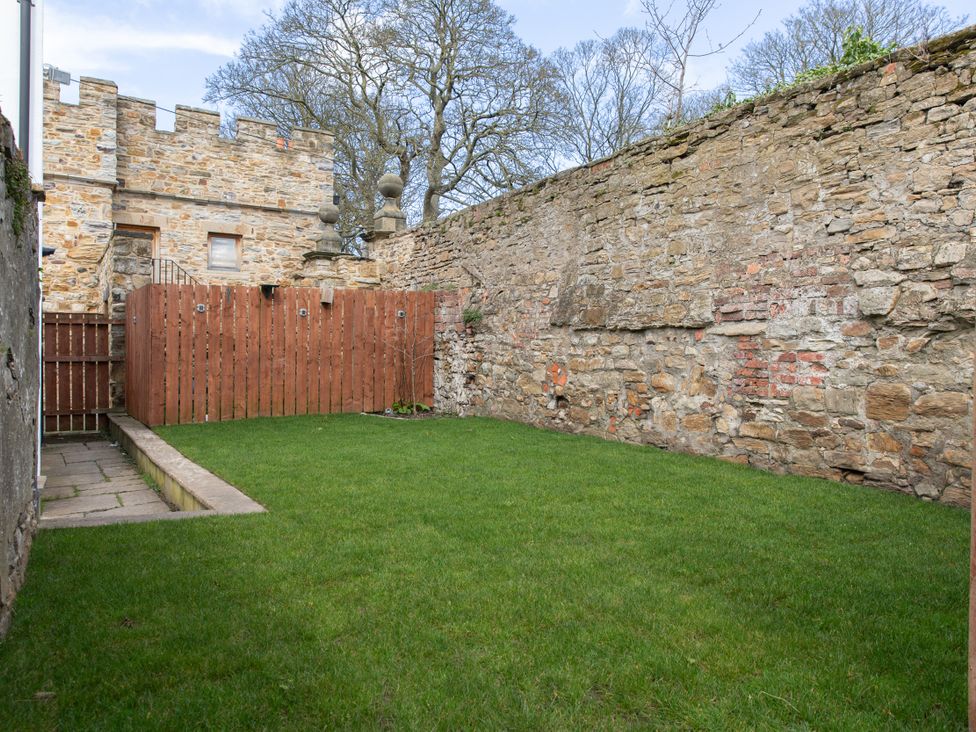 A garden with grass and stone walls at Sheriff's Tower Cottage - East in Bishop Auckland