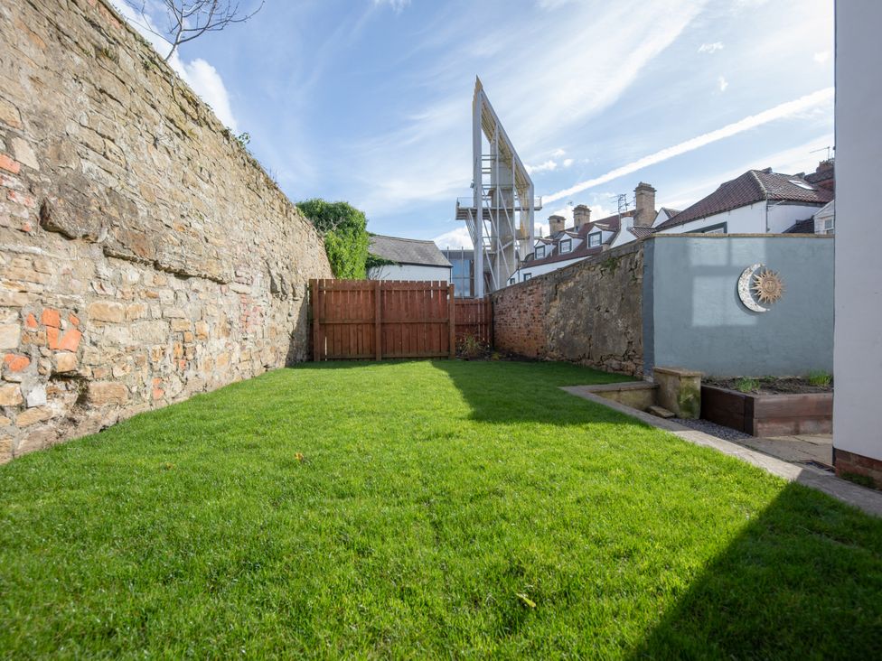 A garden with a grassy area and stone walls at Sheriff's Tower Cottage - East, Bishop Auckland