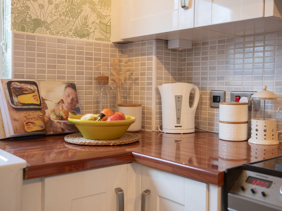 A kitchen countertop with a kettle, fruit bowl, and cookbook at Sheriff's Tower Cottage - West, Bishop Auckland