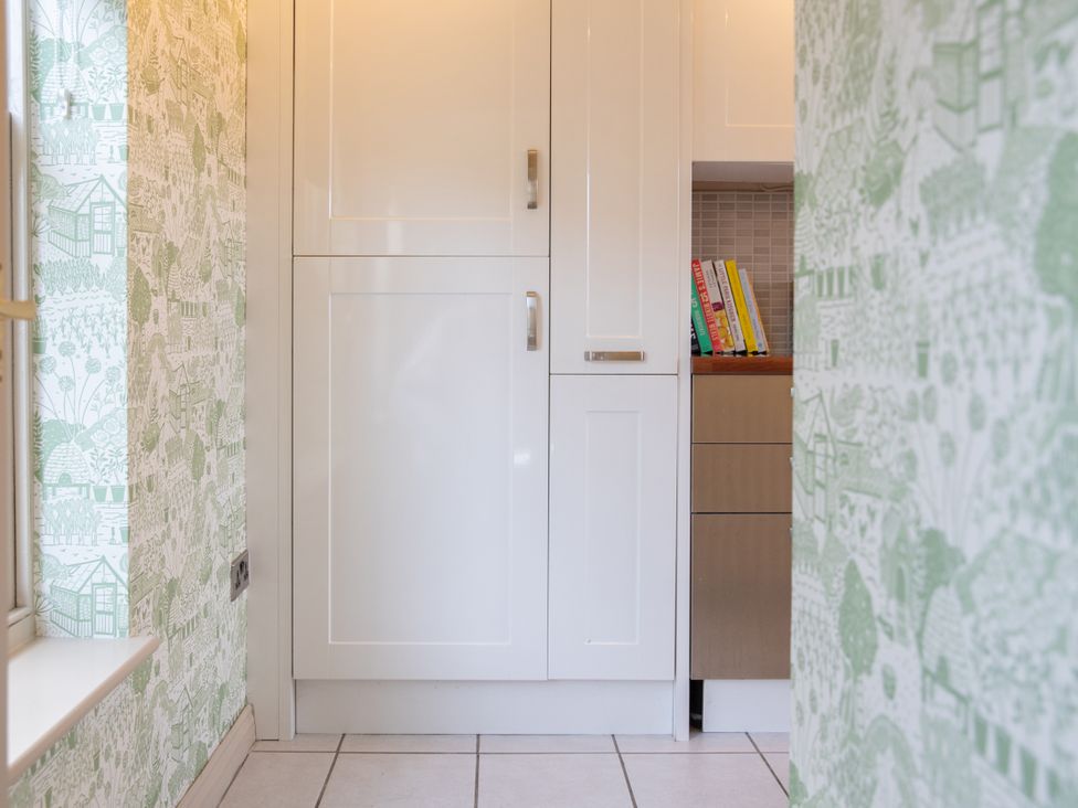 A kitchen featuring storage cupboard and books on a shelf at Sheriff's Tower Cottage - West Bishop Auckland