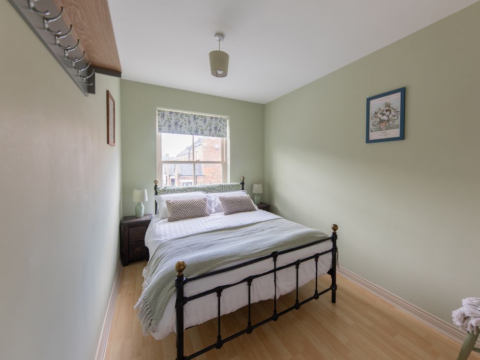 A bedroom with a bed, nightstand, and window at Sheriff's Tower Cottage - West in Bishop Auckland