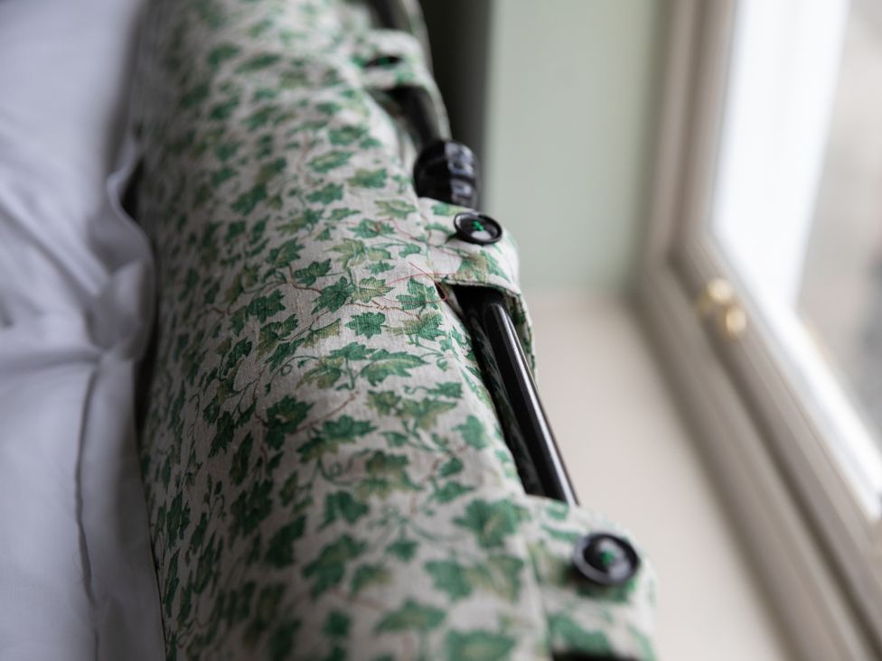 A cushion with a leaf pattern near a window at Sheriff's Tower Cottage - West in Bishop Auckland