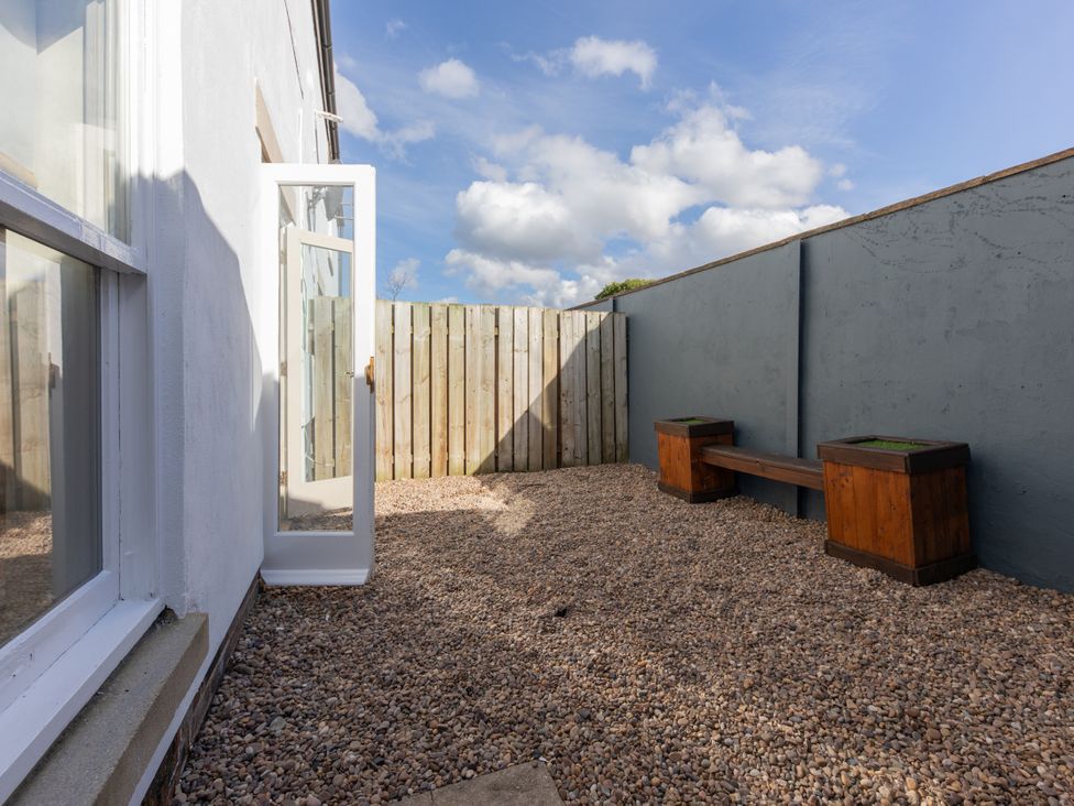 A garden area with gravel and a wooden bench at Sheriff's Tower Cottage - West, Bishop Auckland