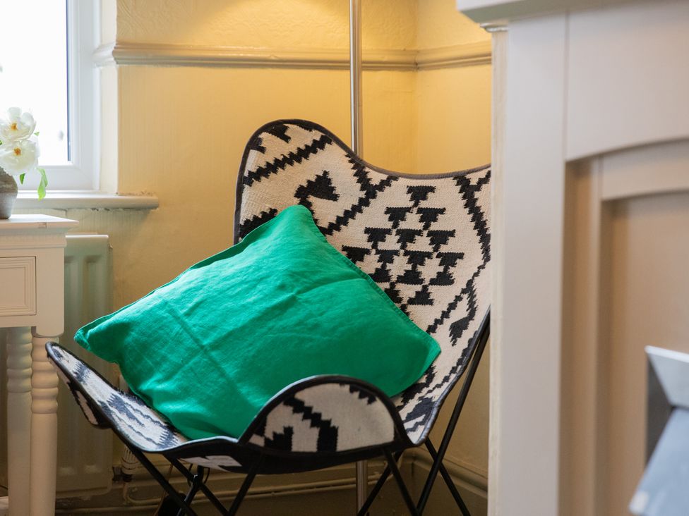 A chair with a cushion next to a side table at No 2 Townhouse in Bishop Auckland