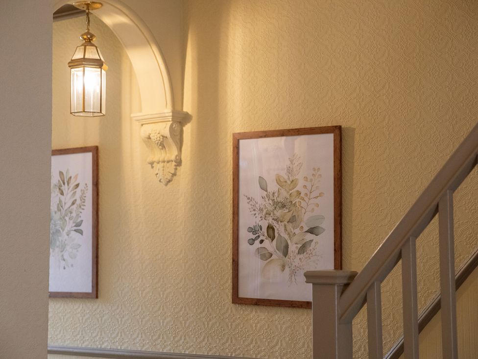 A hallway with framed artwork and a light fixture at No 2 Townhouse in Bishop Auckland