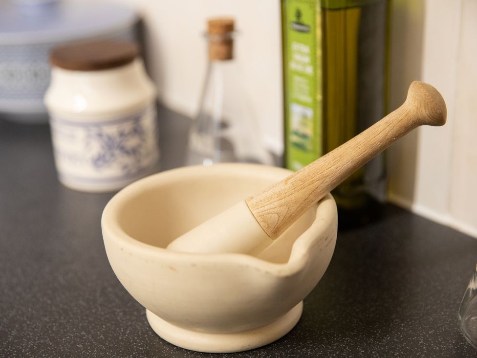 A mortar and pestle with a storage jar and oil bottle in the kitchen at No 2 Townhouse in Bishop Auckland