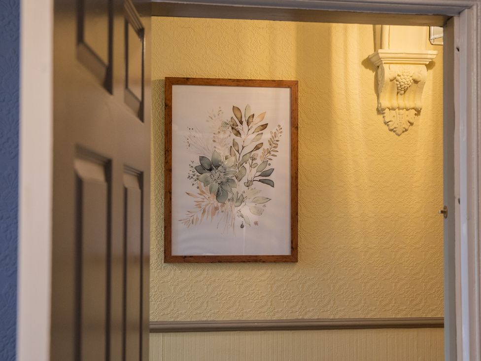 A hallway with wall art and a door at No 2 Townhouse in Bishop Auckland