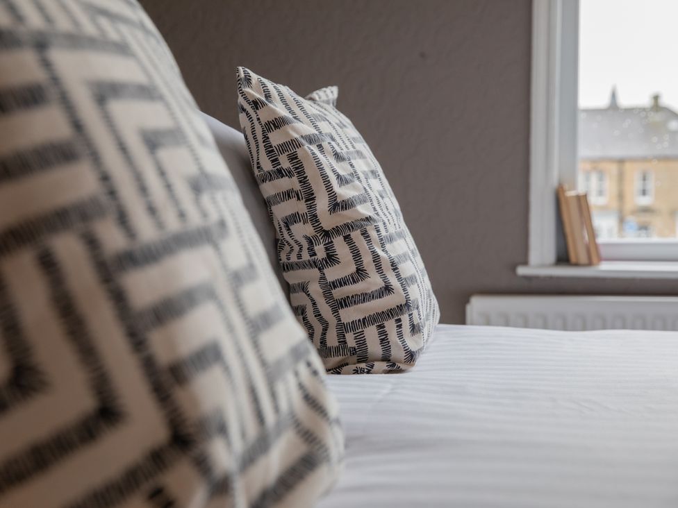 A bedroom with pillows on a bed and a window with books at No 2 Townhouse in Bishop Auckland