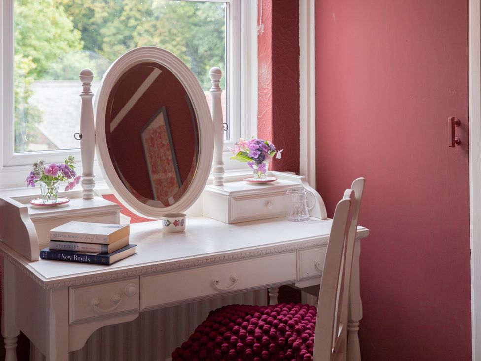 A vanity table with a mirror and flowers at No 2 Townhouse in Bishop Auckland