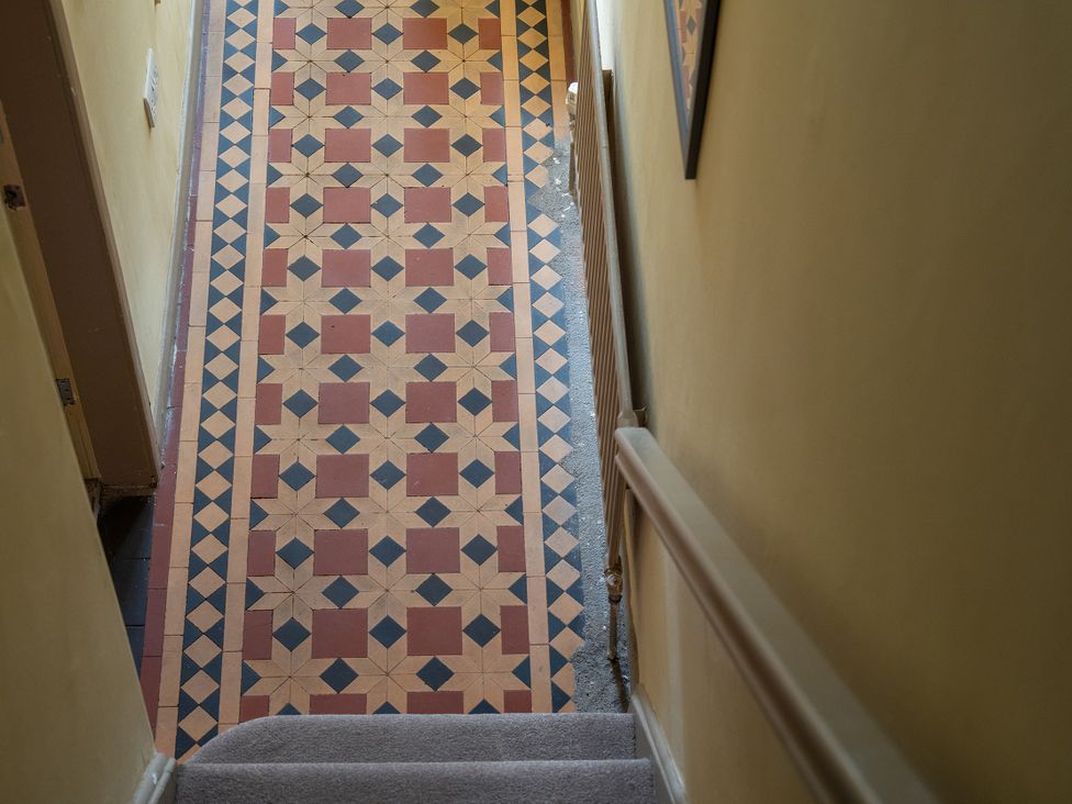A staircase and patterned floor in the hallway at No 4 Townhouse in Bishop Auckland