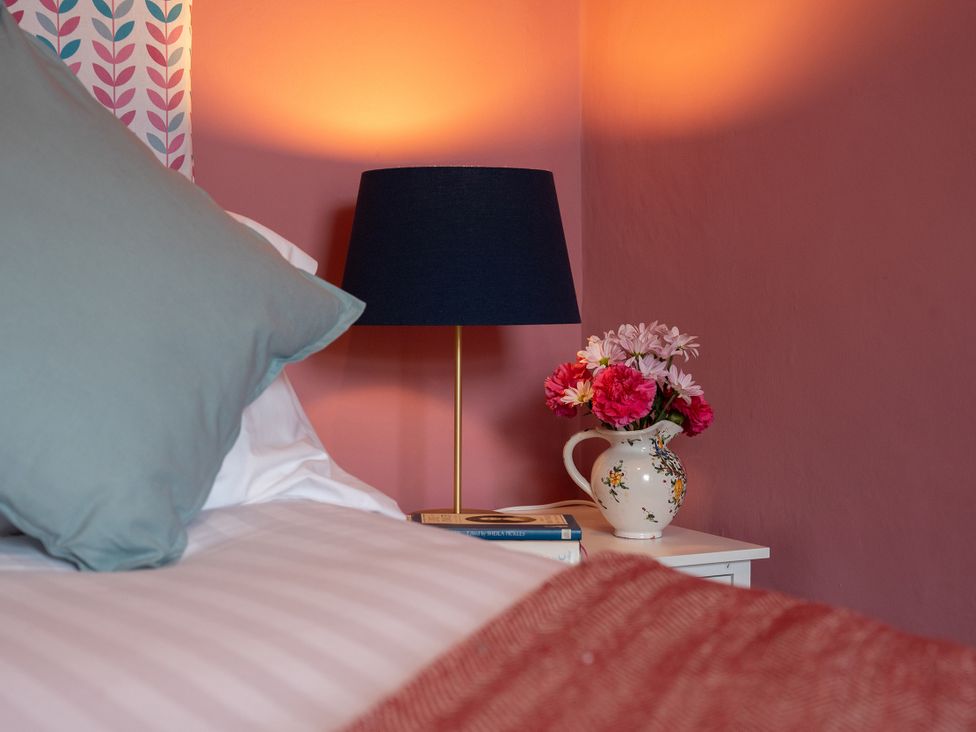 A bedroom with a lamp and flowers on a table at No 4 Townhouse in Bishop Auckland