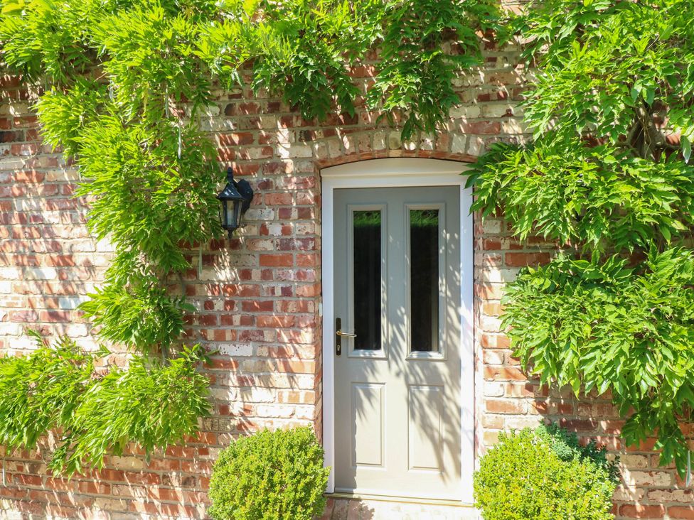 A door with plants and a lantern on a brick wall at Wisteria House in Lincoln