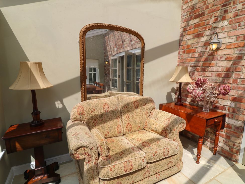 A conservatory with a sofa and lamp at Wisteria House in Lincoln