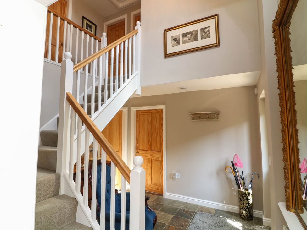 A hallway with a staircase and a mirror at Wisteria House in Lincoln