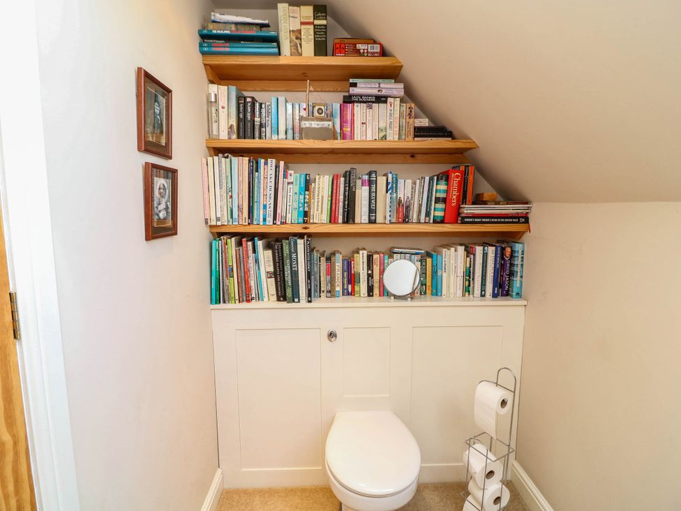 A bathroom with shelves of books and a toilet at Wisteria House in Lincoln