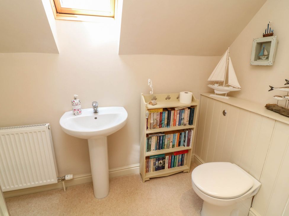 A bathroom with a sink, toilet, and bookshelf at Wisteria House in Lincoln