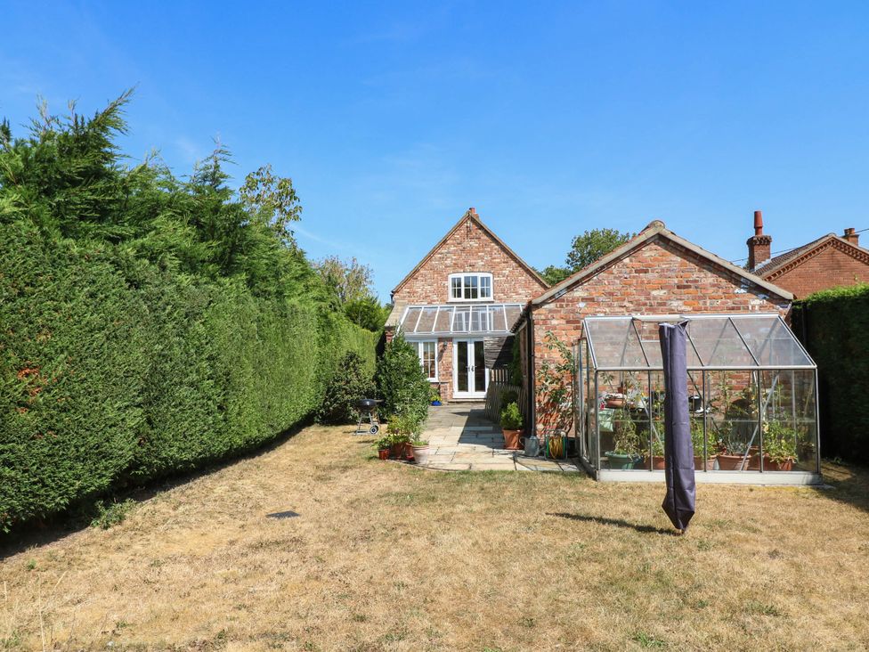 A garden with a house and greenhouse at Wisteria House in Lincoln