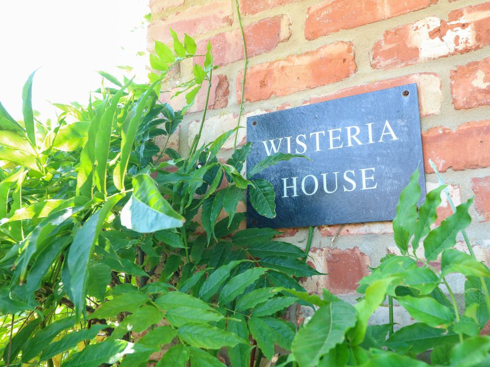A sign on a brick wall labeled Wisteria House in Lincoln