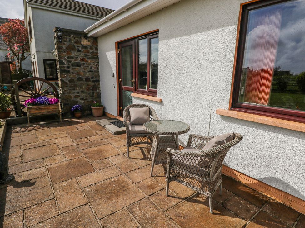 A paved patio with chairs and table outside a house at Harvest Hill in Letterston