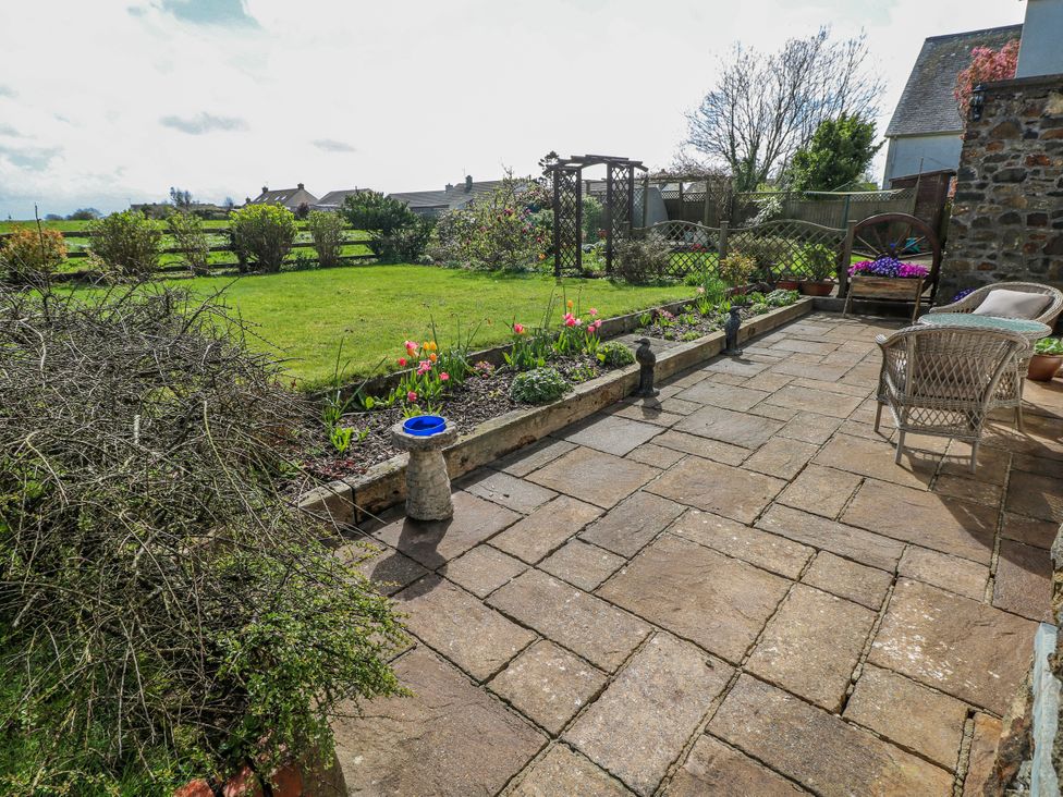 A garden with a patio and flower beds at Harvest Hill in Letterston