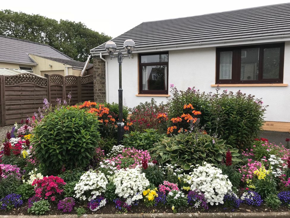 A flower garden with a lamp post in front of a house at Harvest Hill in Letterston