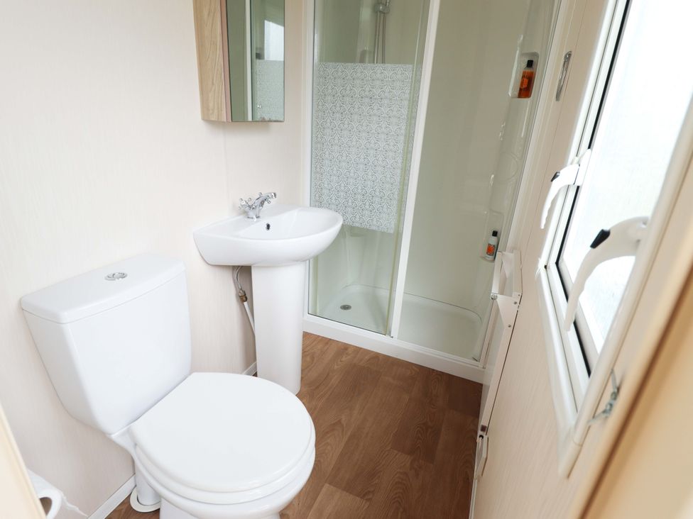 A bathroom with a toilet, sink, and shower at The Seafront Cosy Caravan in Ingoldmells