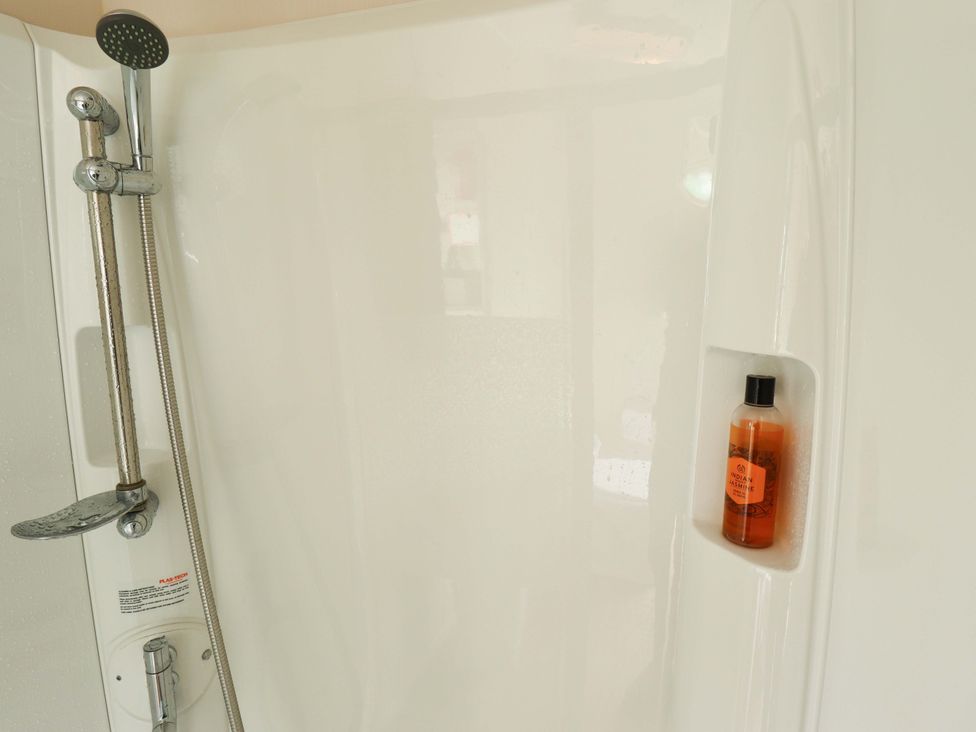 A shower with a shower head and a shampoo bottle at The Seafront Cosy Caravan in Ingoldmells