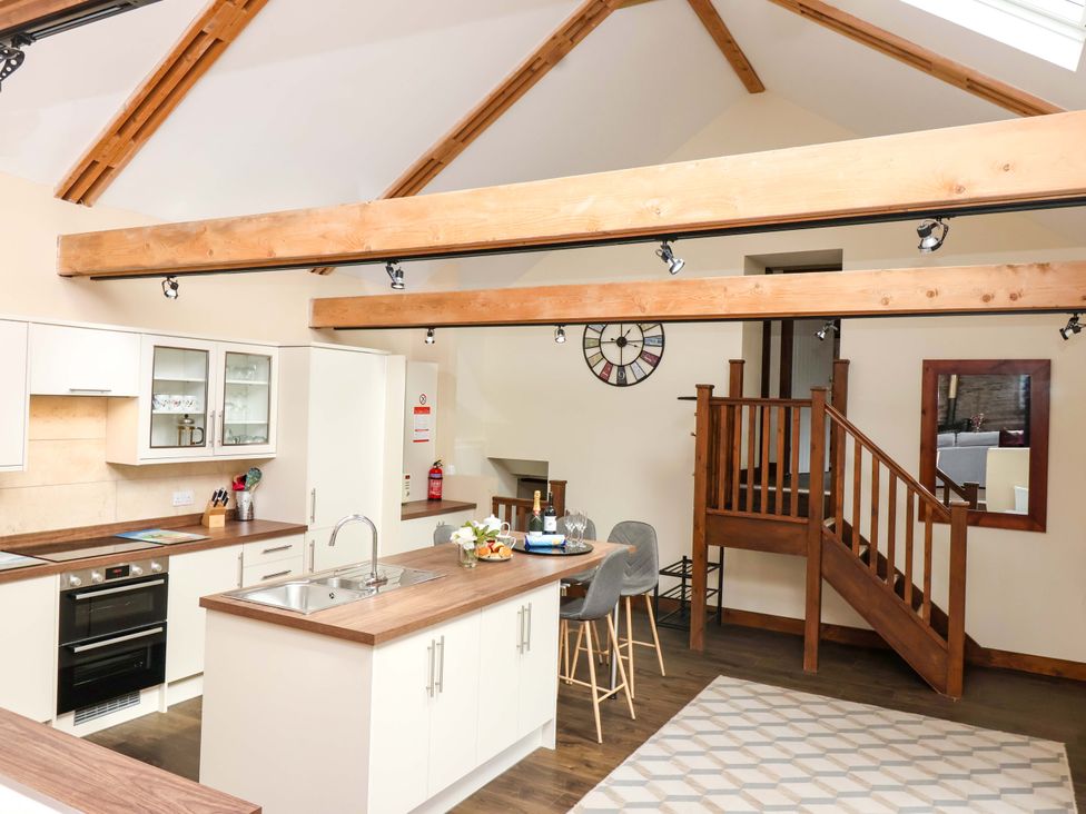 A kitchen with a staircase and bar stools at Cider Press Cottage in Torpoint