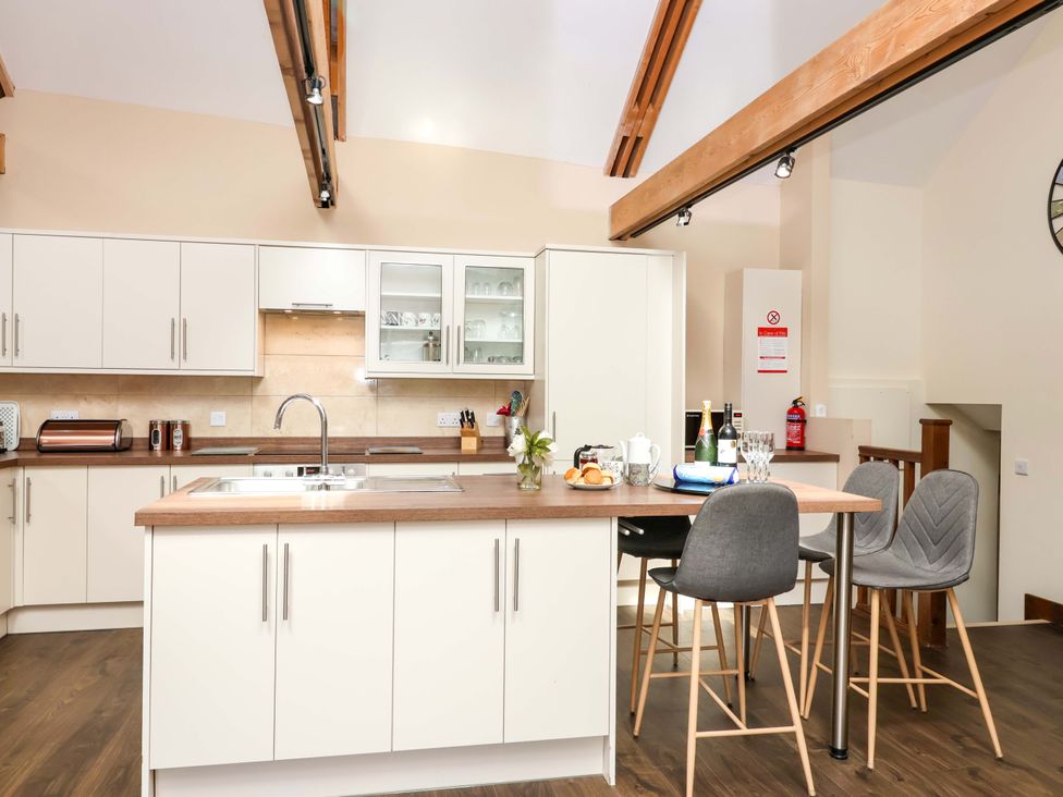 A kitchen with a sink and bar stools at Cider Press Cottage in Torpoint