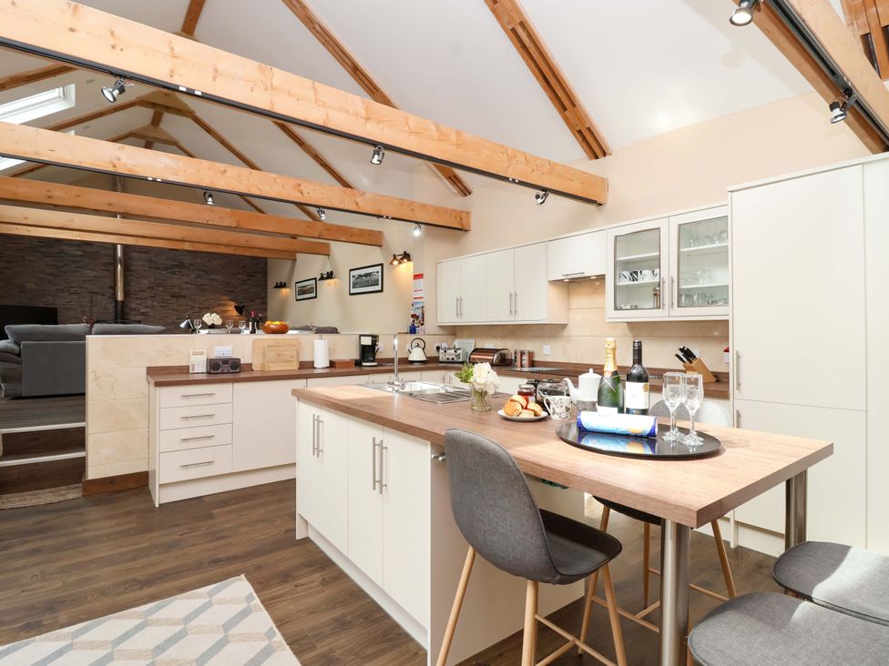 A kitchen with bar stools and appliances at Cider Press Cottage in Torpoint