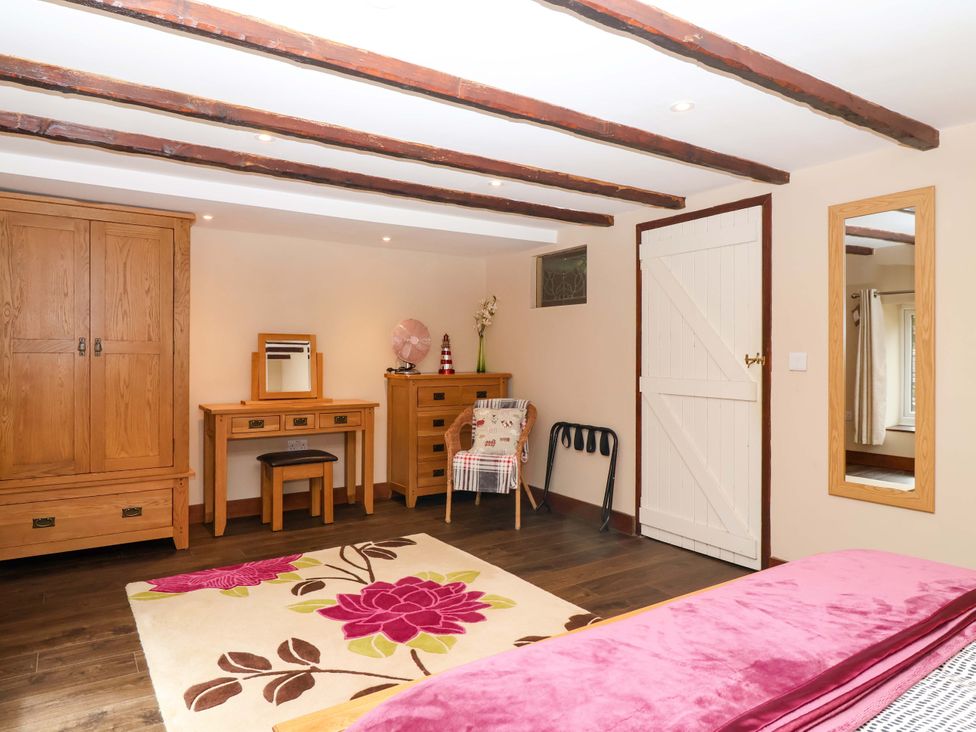 A bedroom with a wardrobe and a desk at Cider Press Cottage Torpoint