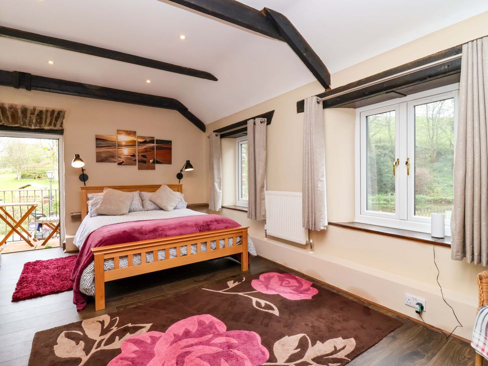 A bedroom with a bed and windows at Cider Press Cottage Torpoint