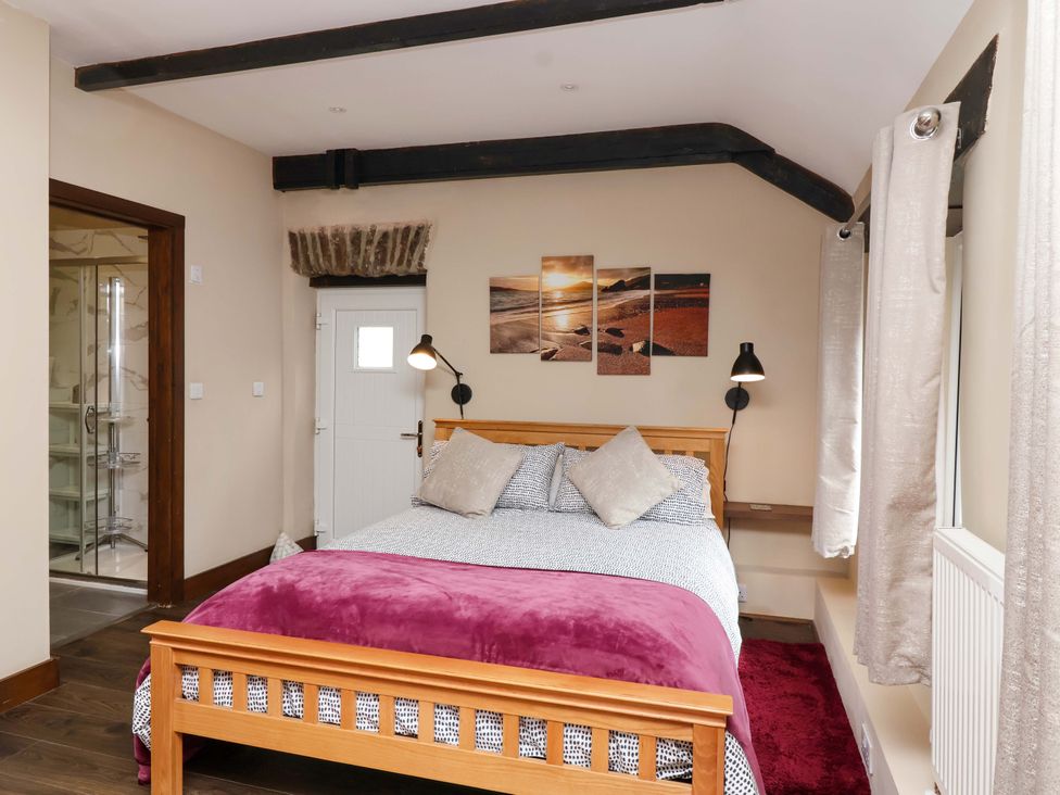 A bedroom with a bed and wall art at Cider Press Cottage in Torpoint