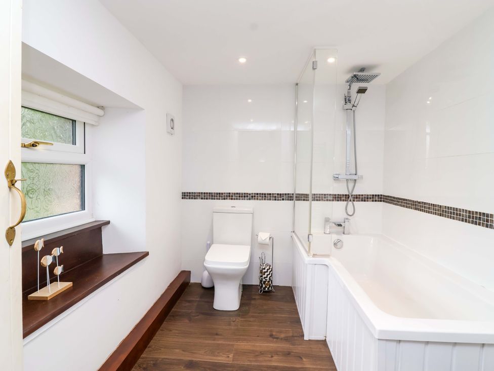 A bathroom with a toilet and bathtub at Cider Press Cottage in Torpoint