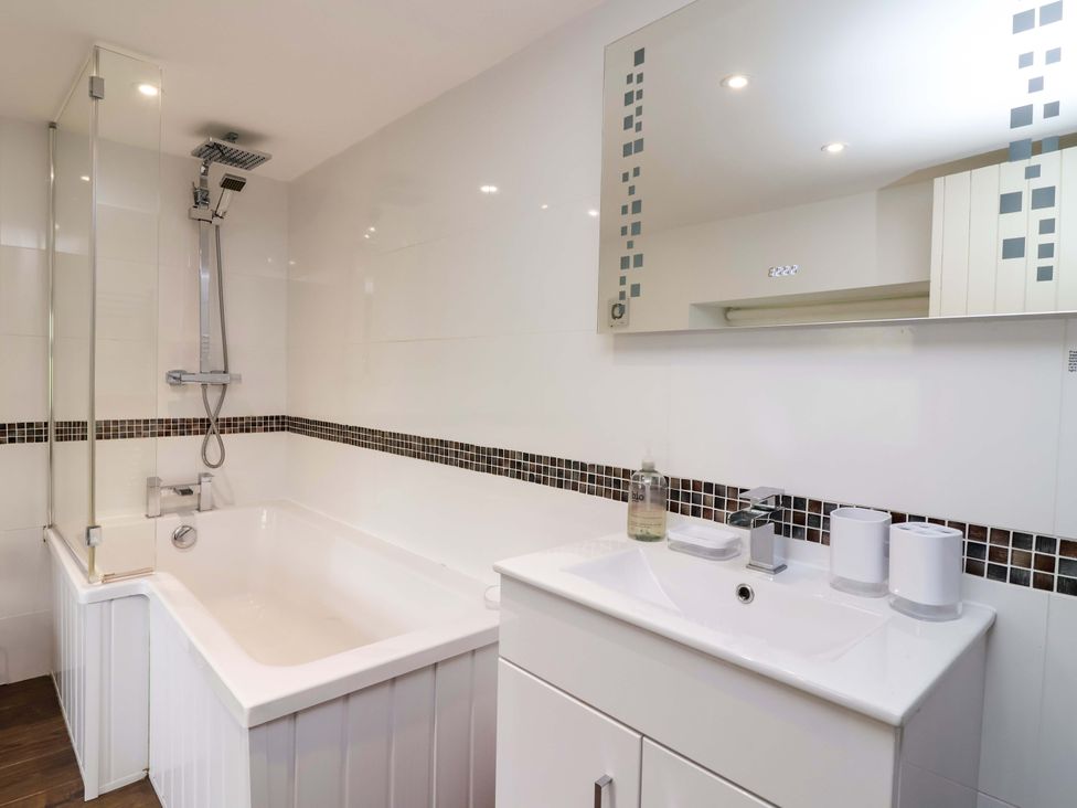 A bathroom with a bathtub and sink at Cider Press Cottage in Torpoint