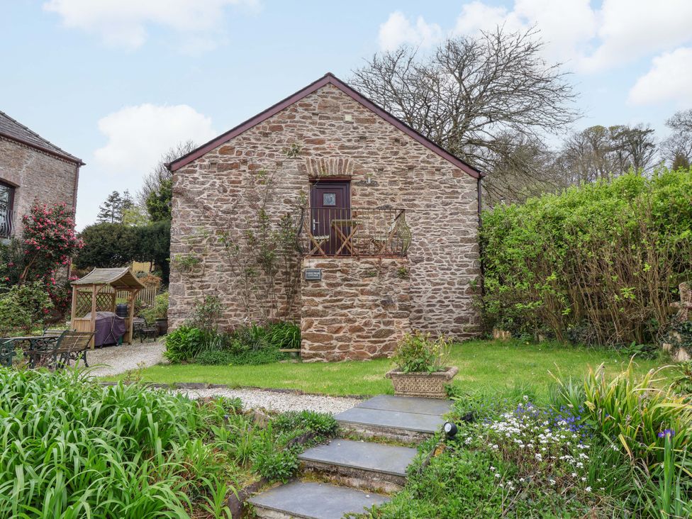 A stone building with a balcony and garden at Cider Press Cottage Torpoint