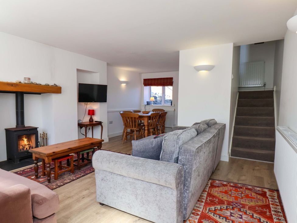 A living room with a sofa, dining table, and fireplace at Cozy Cottage