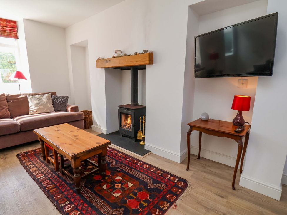 A living room with a sofa, coffee table and fireplace at Cozy Cottage